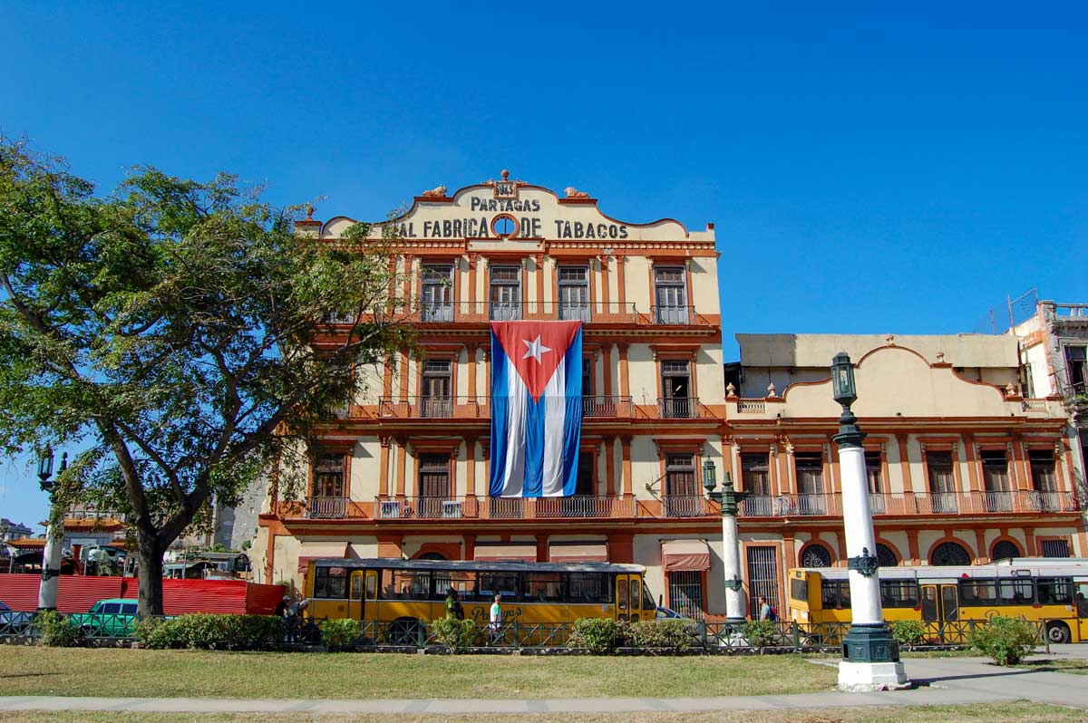large old factory building with cuban flag behind city square