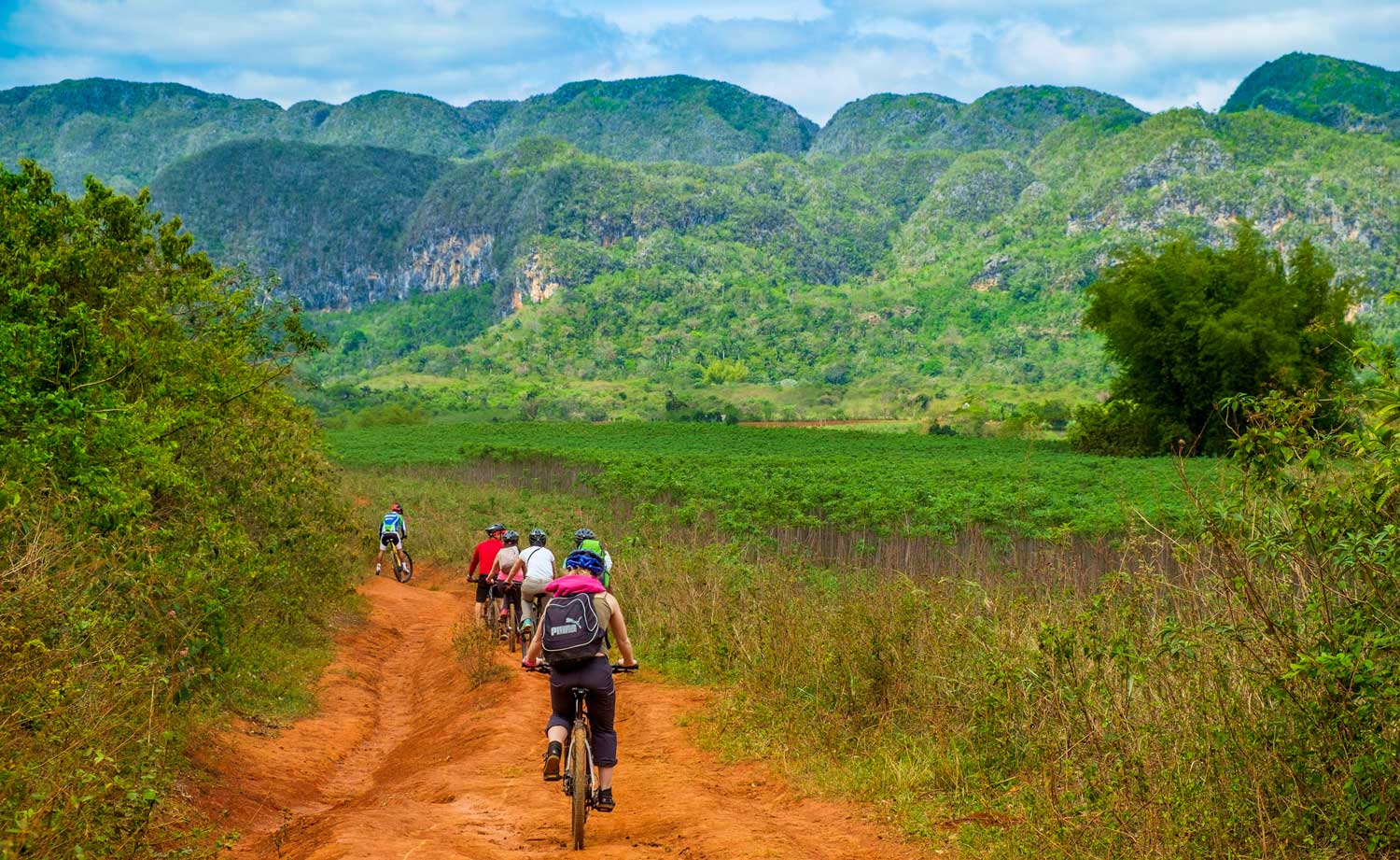group of mountain bikers on red dirt path in mountainous valley